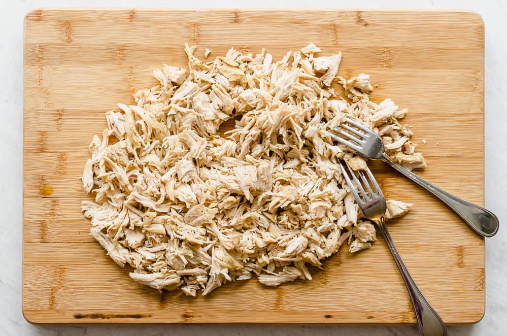 Shredded chicken on a wooden cutting board.