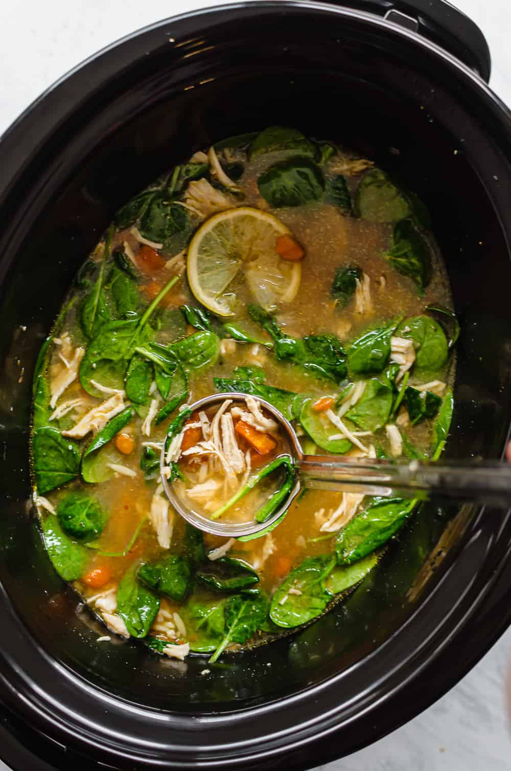 Lemon chicken Orzo soup being ladled out of the crockpot.