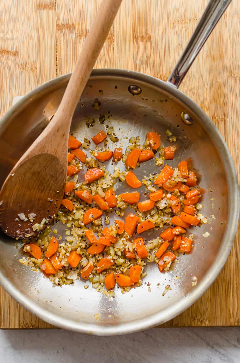 Sauteed onions, carrots, and garlic in a a stainless steel frying pan.