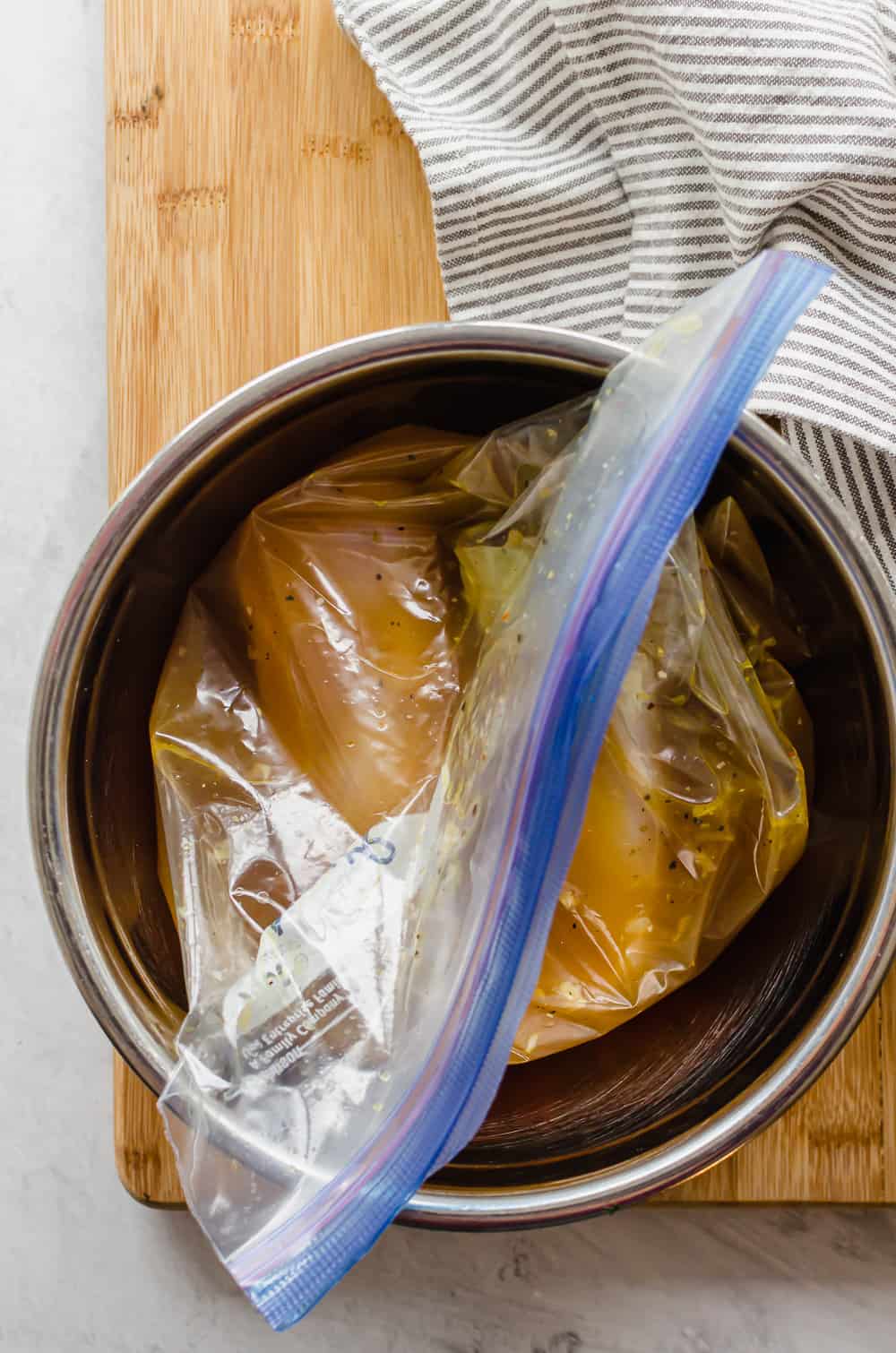 A freezer bag filled with chicken breasts and chicken broth