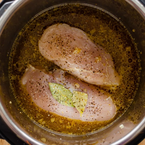 two chicken breasts and some broth and bay leaves in the Instant Pot