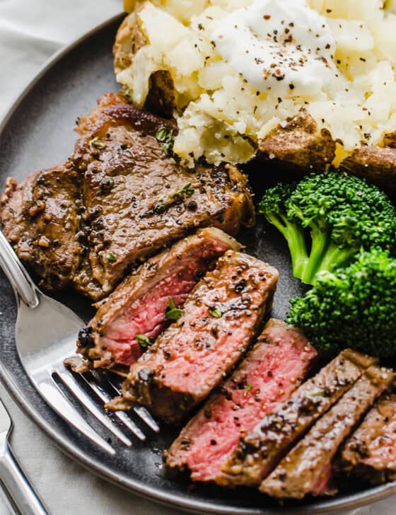 Pan-seared, oven-finished steak with potato and broccoli on a plate.