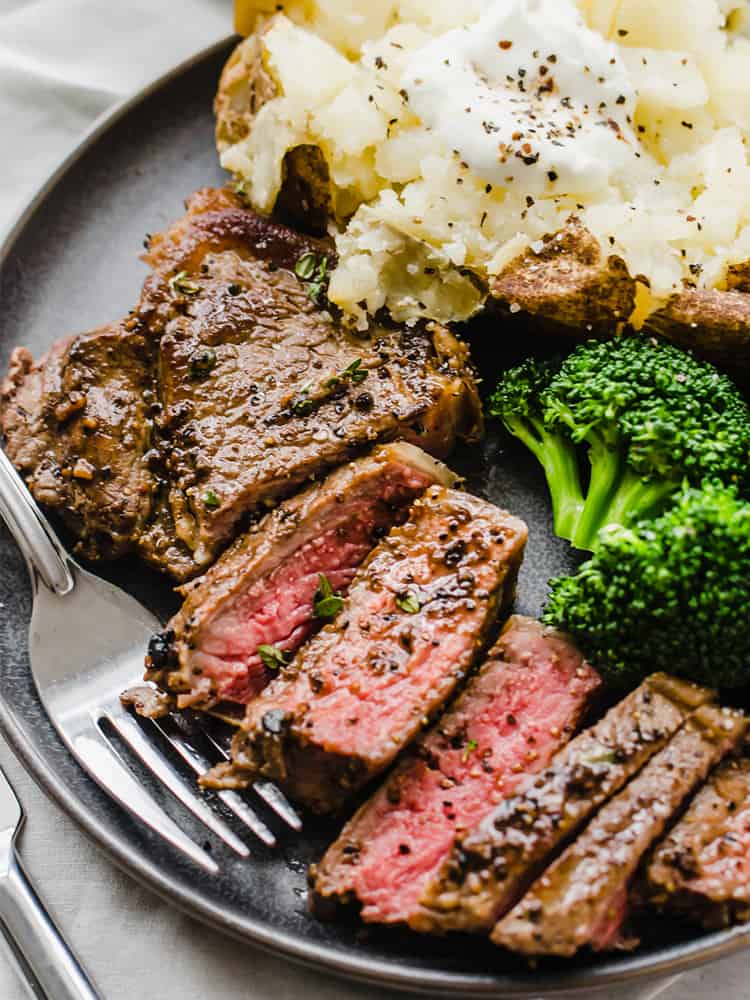 Pan-seared, oven-finished steak with potato and broccoli on a plate.