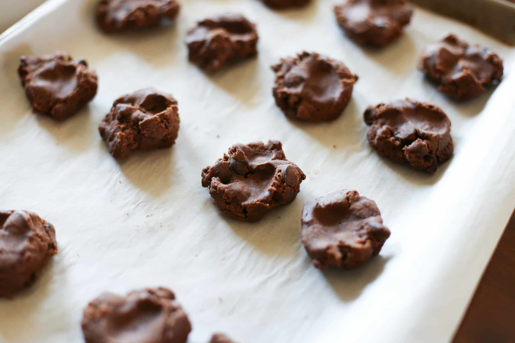 Dark chocolate coffee cookie dough scooped on to a baking sheet ready for the oven.