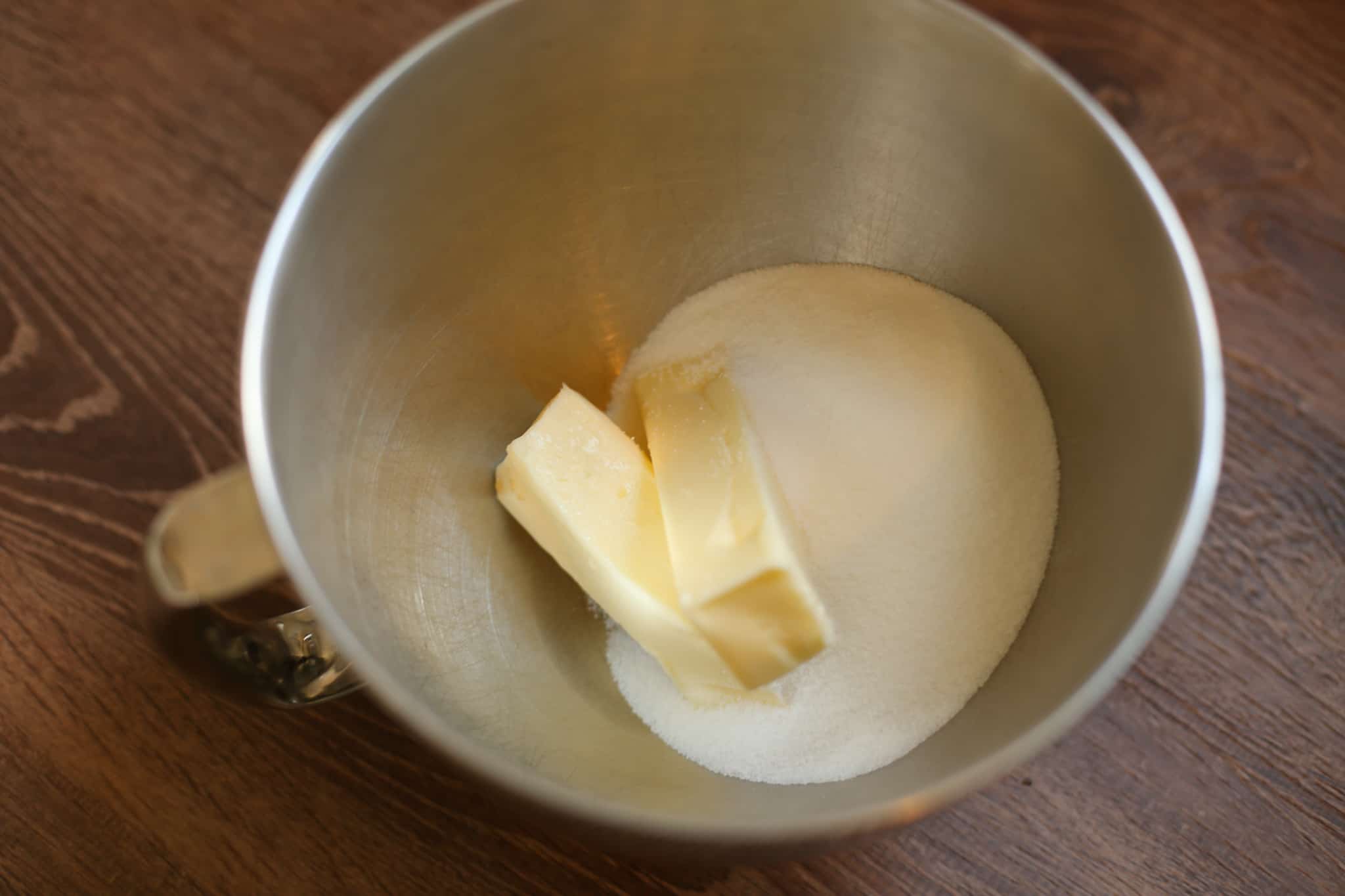 Sugar and two sticks of butter in a metal mixing bowl.