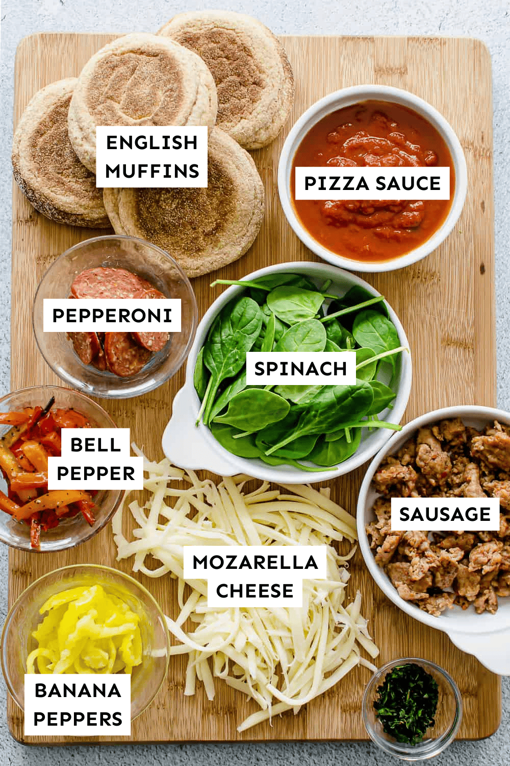 English muffin pizza ingredients laid out on a cutting board and labeled.