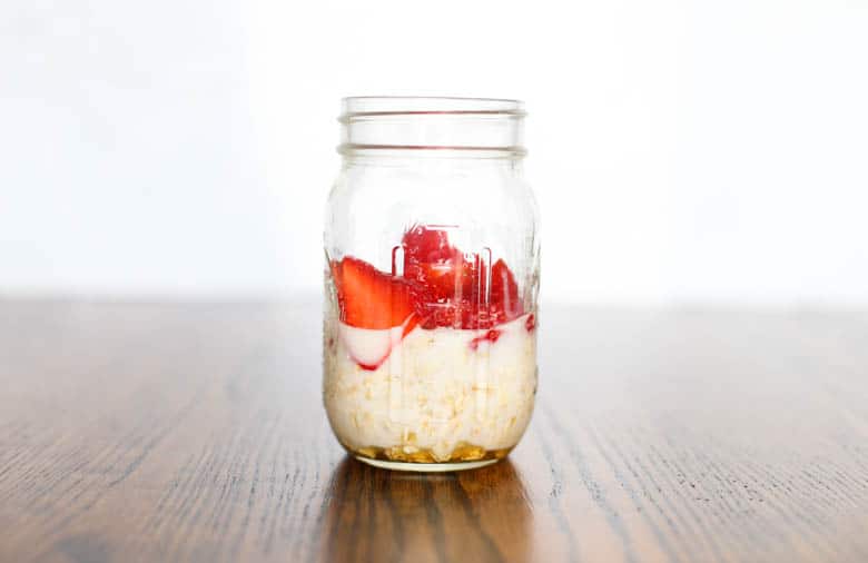 Strawberries added to overnight oats in a mason jar. 