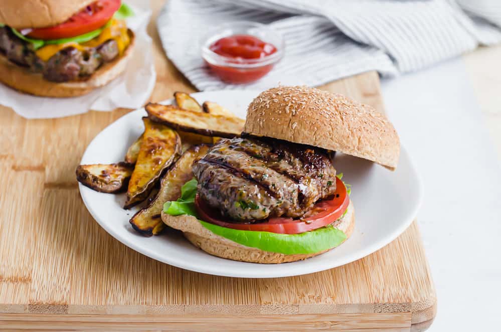 grilled burger on a bun with oven fries on the side