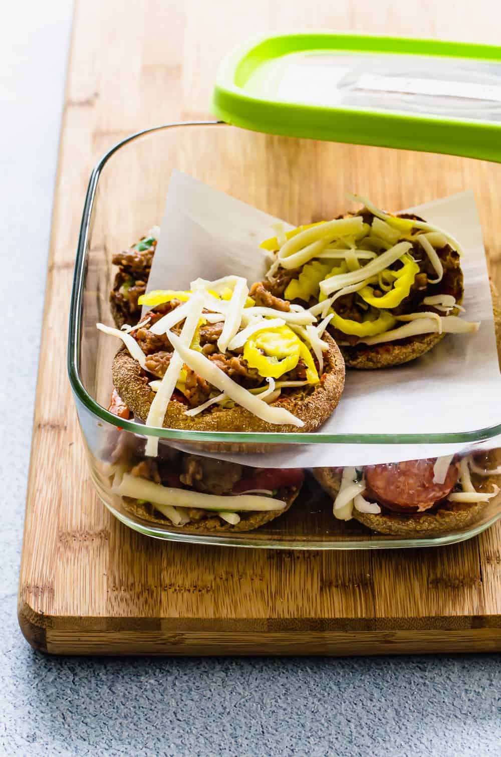 English muffin pizzas layered in a freezer container before being cooked, 