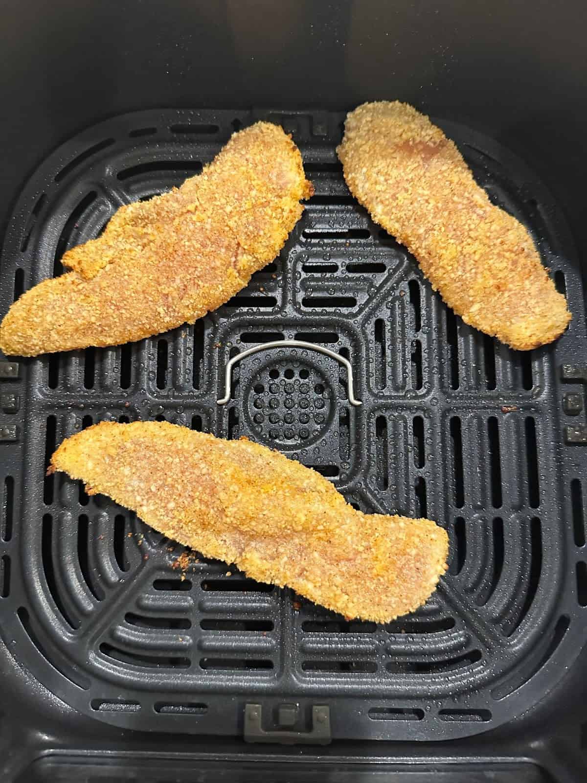 Raw, breaded chicken tenders in the air fryer.
