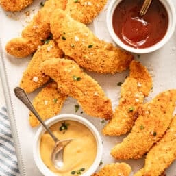Baked Parmesan Chicken tenders on a sheet pan with dipping sauces.