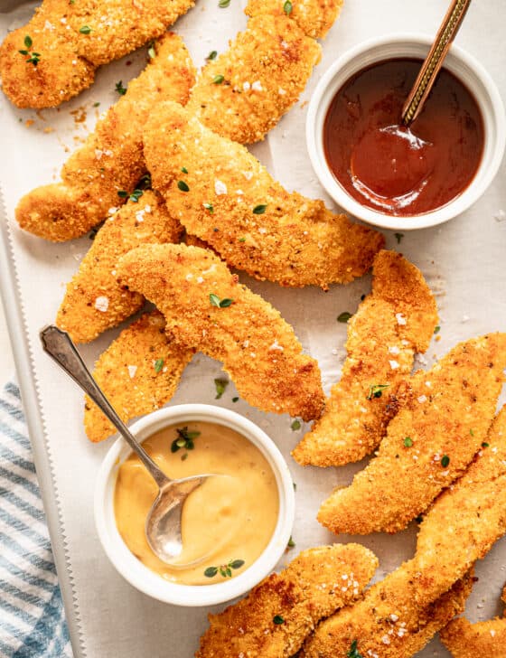 Baked Parmesan Chicken tenders on a sheet pan with dipping sauces.