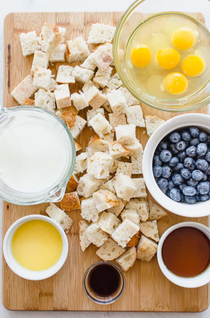 ingredients for blueberry french toast bake, including bread, blueberries, eggs, milk, butter, and maple syrup