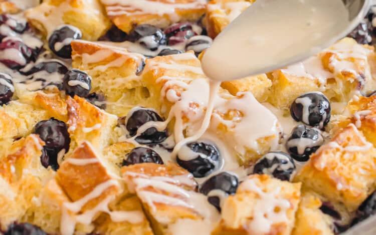 vanilla glaze being drizzled on top of a blueberry baked french toast casserole