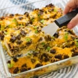 A slice of breakfast casserole with hash browns being served with a spatula.