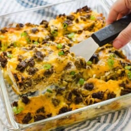 A slice of breakfast casserole with hash browns being served with a spatula.
