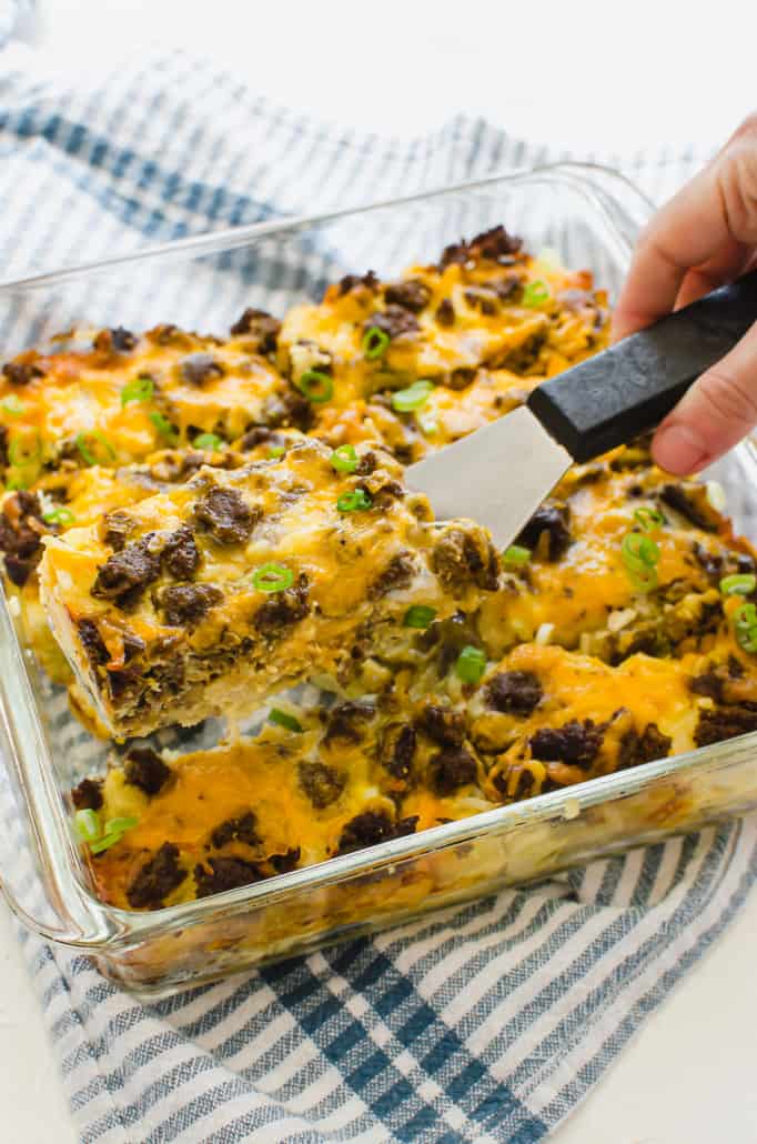 a slice of breakfast casserole with hash browns being served with a spatula