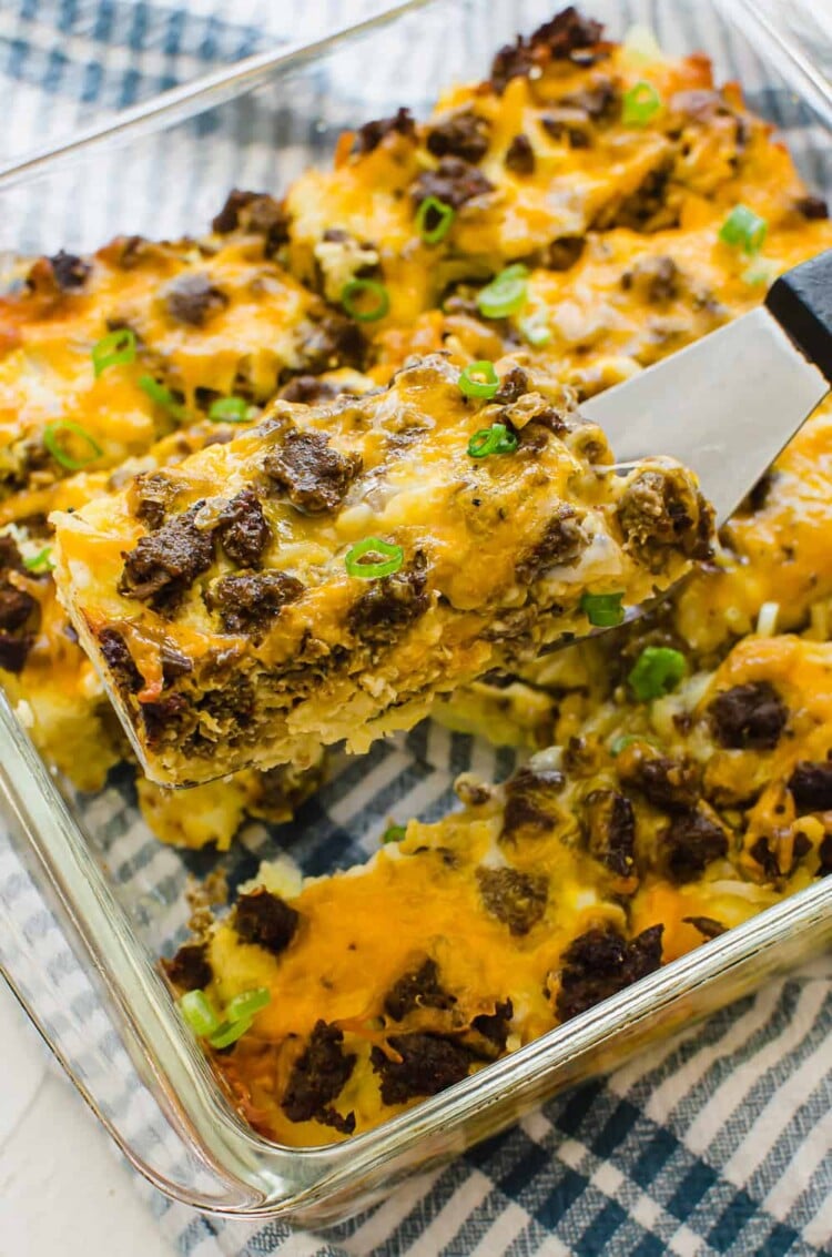 A slice of breakfast casserole with hash browns being served with a spatula.