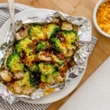 Chicken foil packet with broccoli, bacon, and rice open on a plate ready to eat.