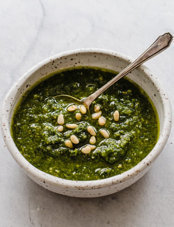 Bowl of freshly made pesto with pine nuts sprinkled on top.