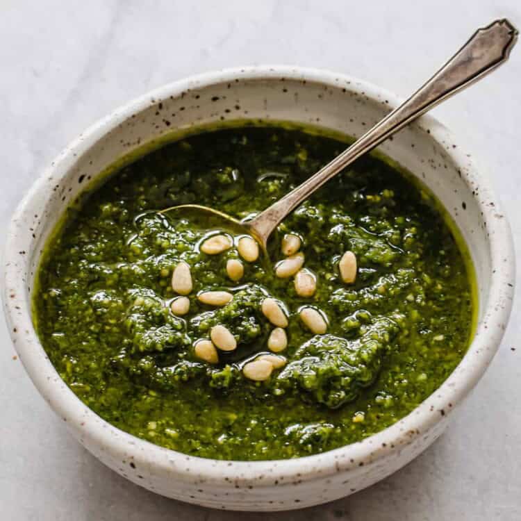 Bowl of freshly made pesto with pine nuts sprinkled on top.