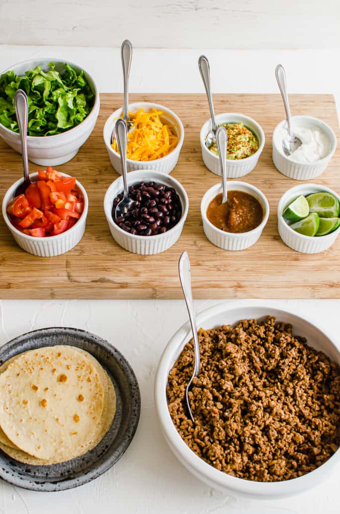 taco bar ingredients set out on a wooden cutting board