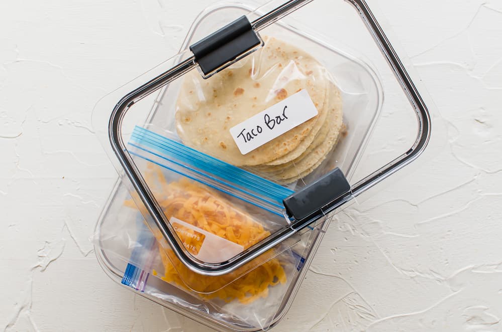 Taco bar ingredients measured into freezer bags and all placed into a freezer-safe container to keep them together as a kit.