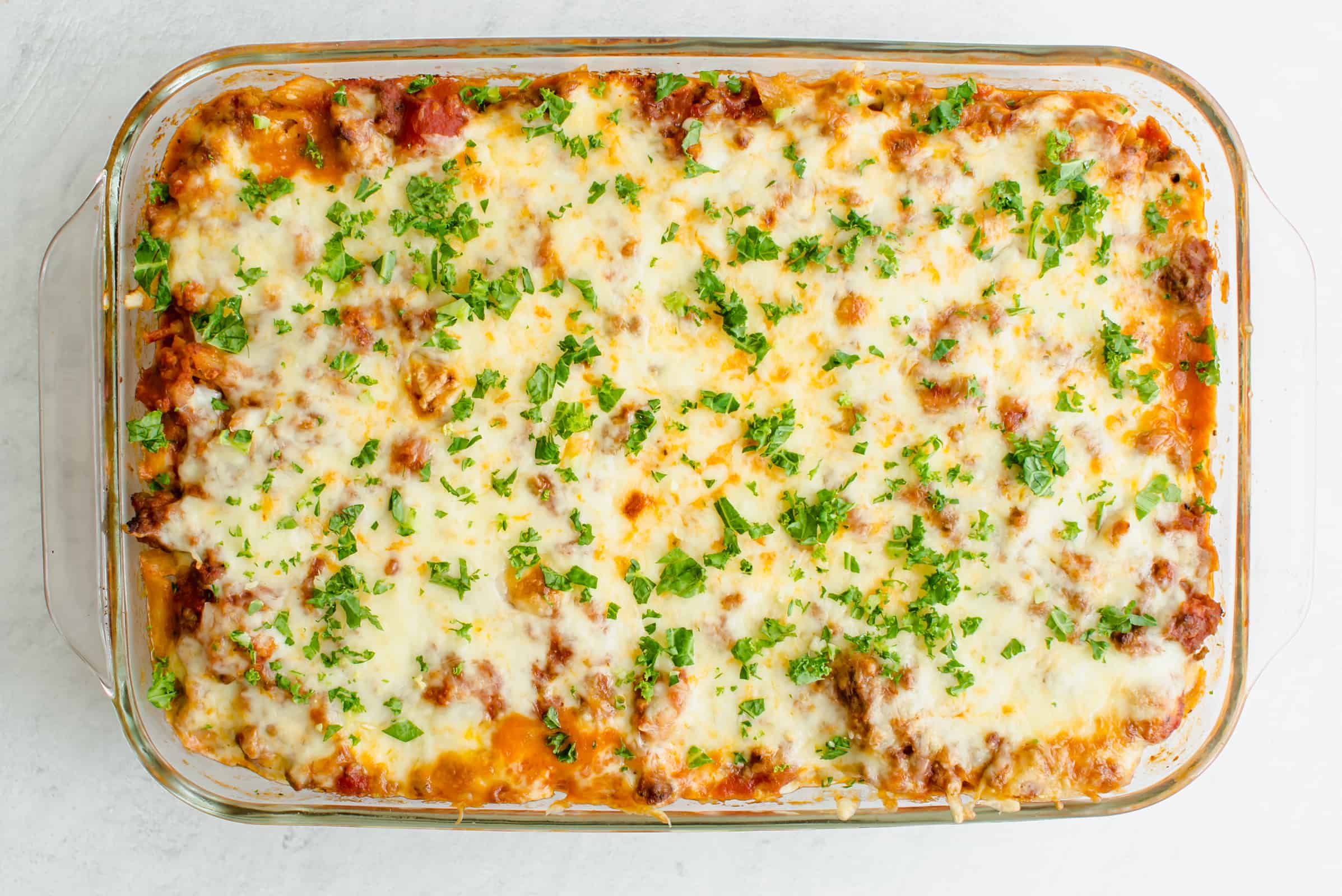 Baked penne pasta in a glass baking dish.