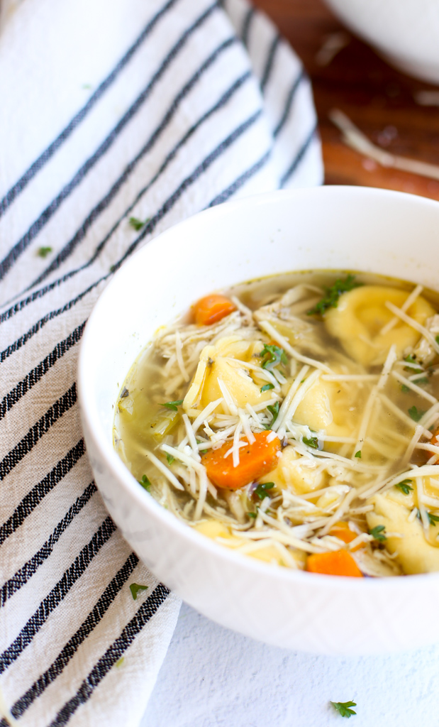 Chicken tortellini soup topped with parmesan cheese and parsley 
