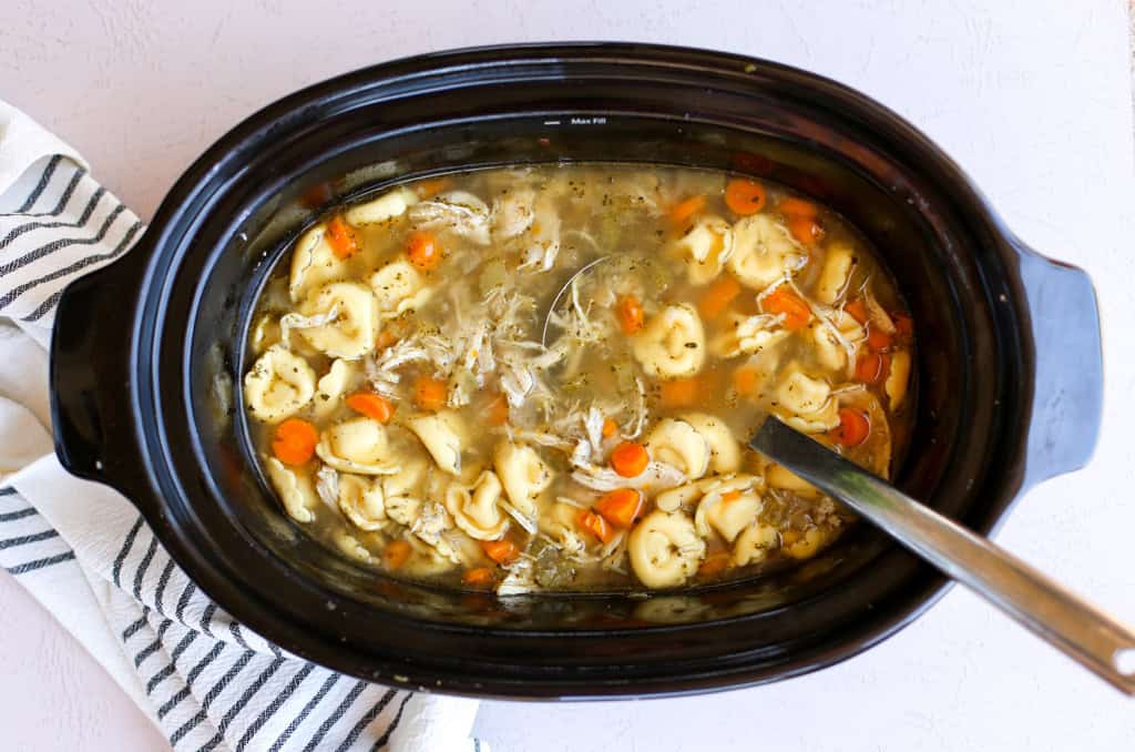 A slow cooker full of chicken tortellini soup.