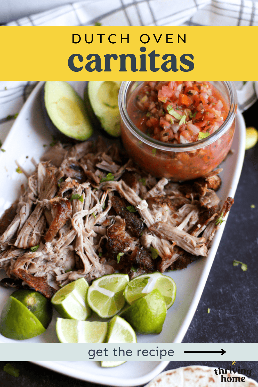 Platter of carnitas with lime wedges and a small bowl of salsa.