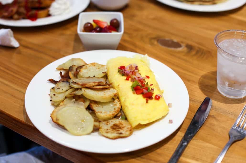 Omelet and home-style potatoes on a white plate