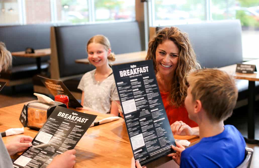 family laughing around a table and looking at a breakfast menu