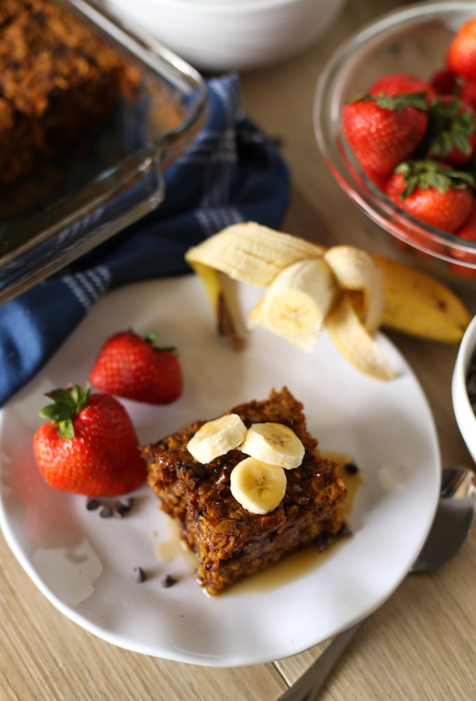 Slice of Pumpkin Baked Oatmeal on a white plate with banana slices on top and strawberries next to it.