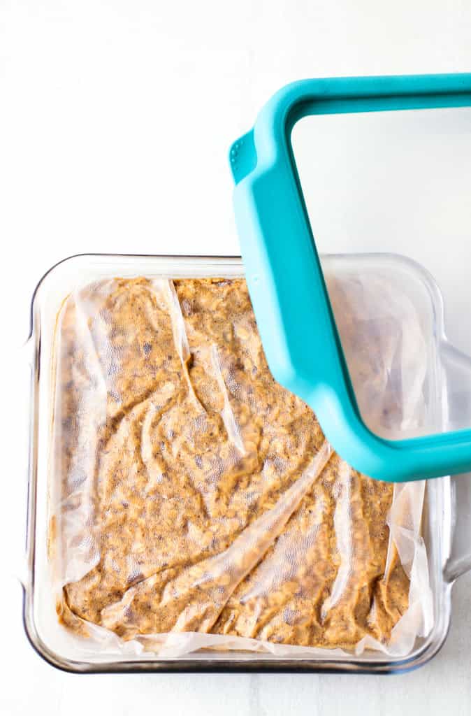 Baked Oatmeal in a glass casserole dish covered by plastic wrap with a glass lid being placed on top.