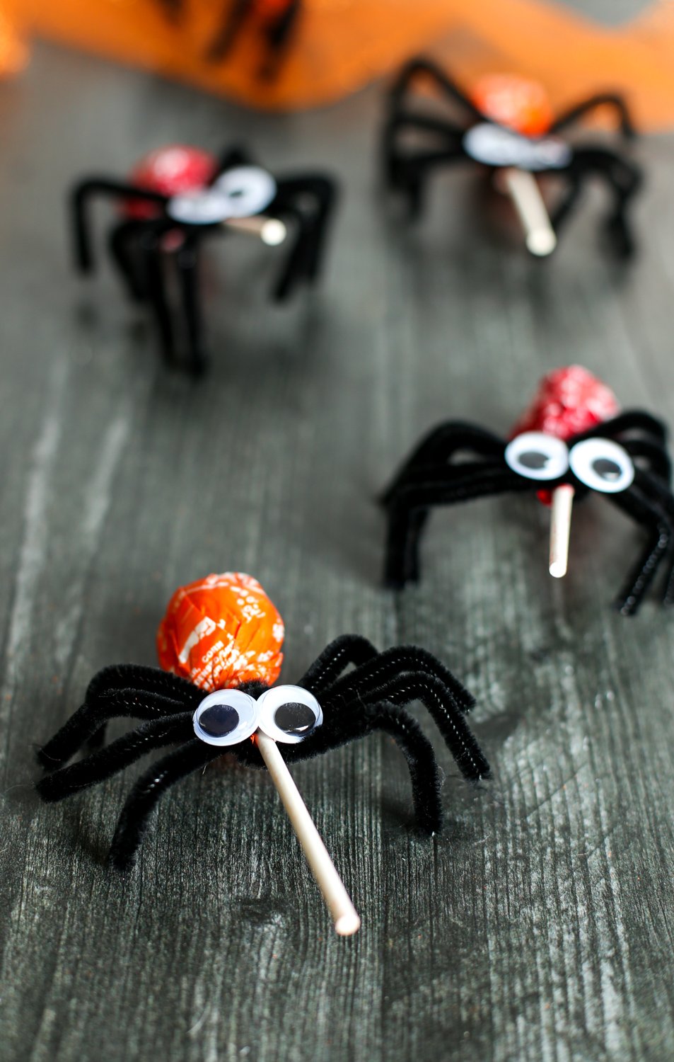 Lollipop spider Halloween craft - black pipe cleaners wrapped around a lollipop to look like spider legs and then googly eyes on top.
