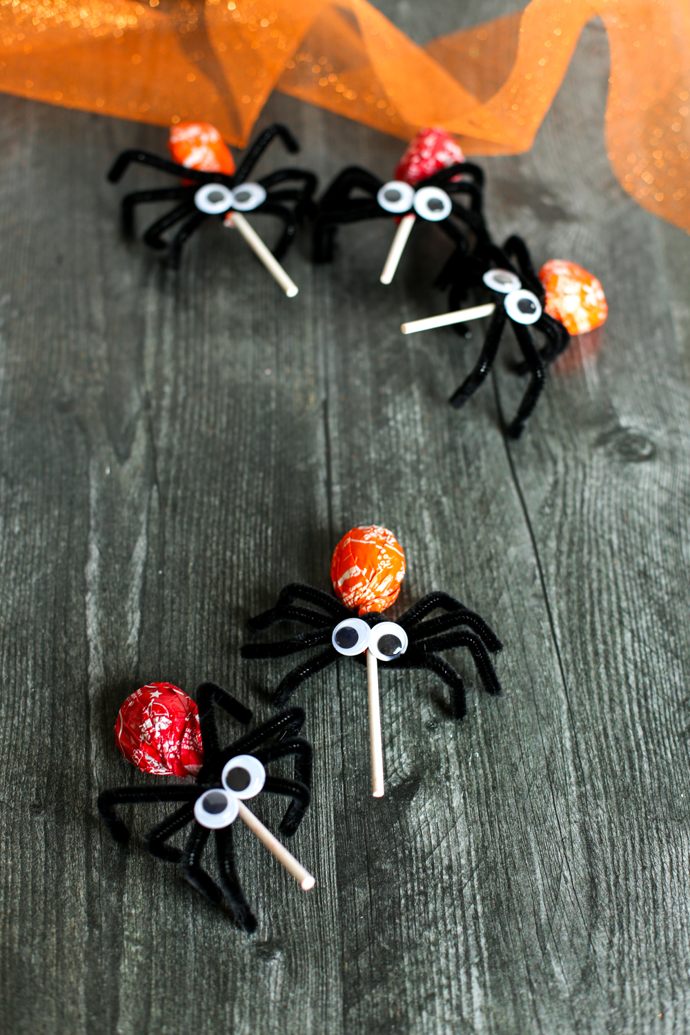 Two spider lollipops on a wooden table.