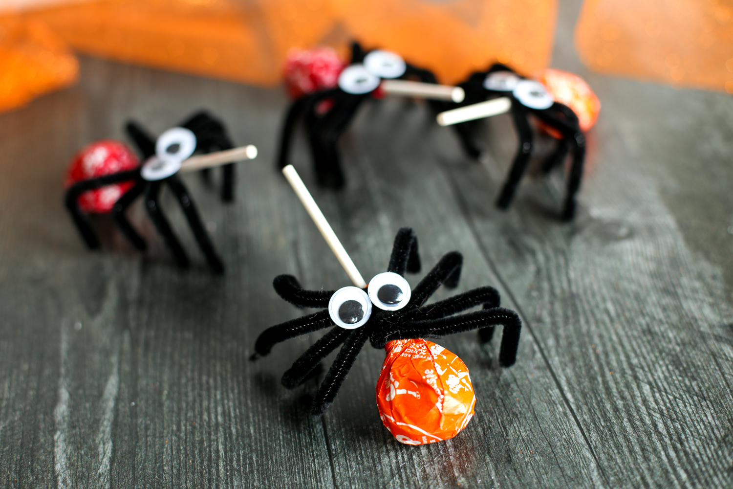 Spider lollipops sitting on a wooden table.