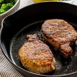 Pan-seared pork chops in a cast iron pan.