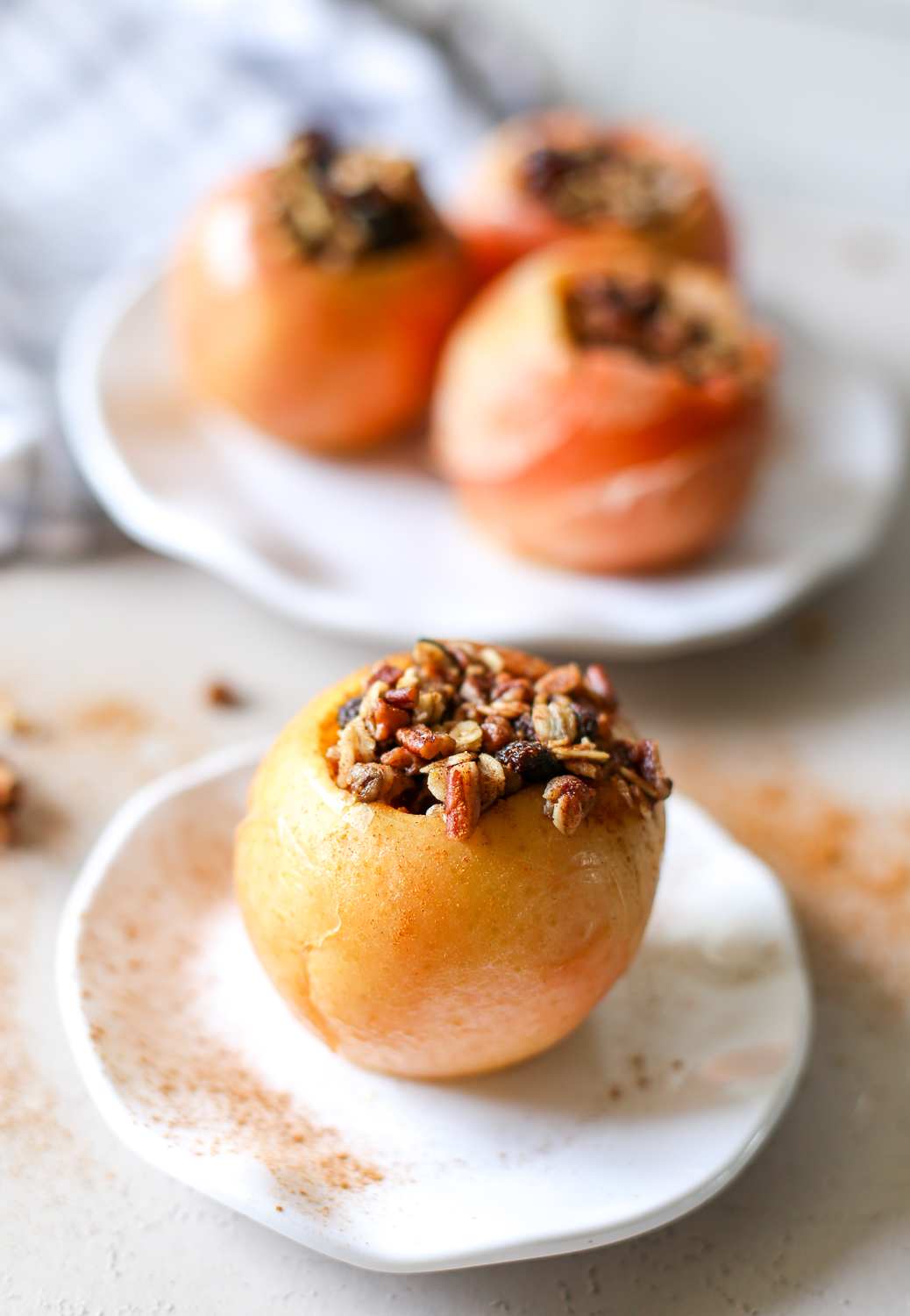 A baked apple on a plate filled with oats, pecans, cinnamon, and more.
