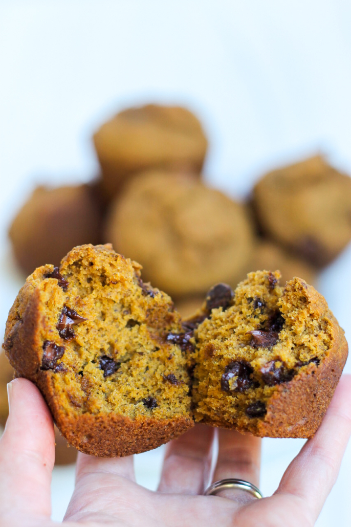 hand holding a pumpkin chocolate chip muffin that's broken in half to show the interior