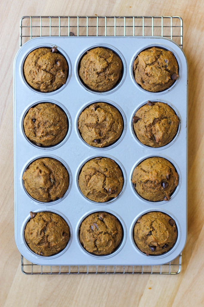 pumpkin chocolate chip muffins in a tin on a cooling rack