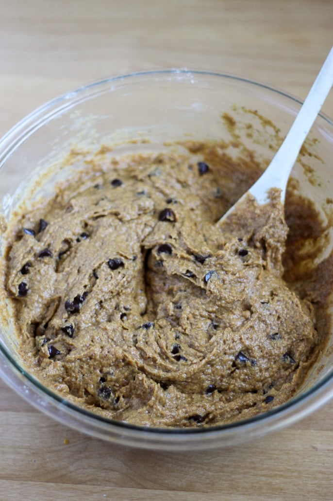 muffin batter with chocolate chips in a mixing bowl with wooden spoon