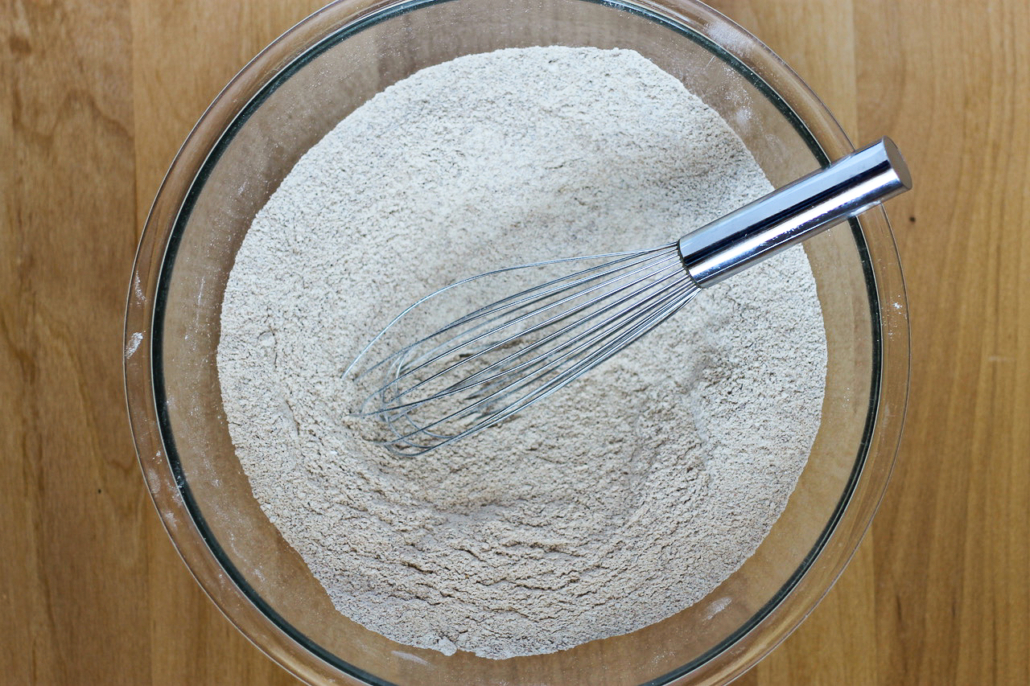 dry ingredients for muffins in a glass bowl with whisk