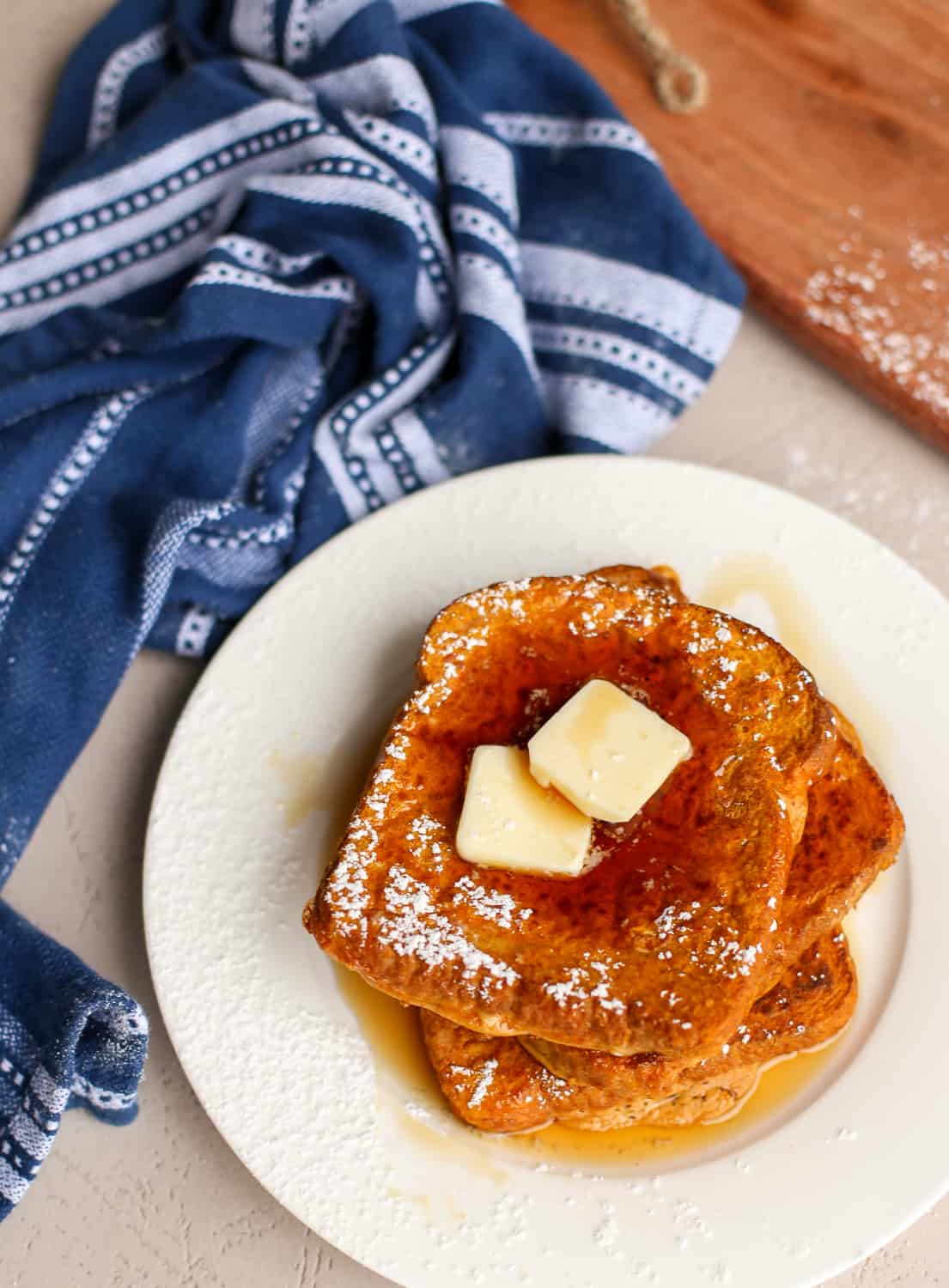 Pumpkin french toast on a white plate with butter on top.