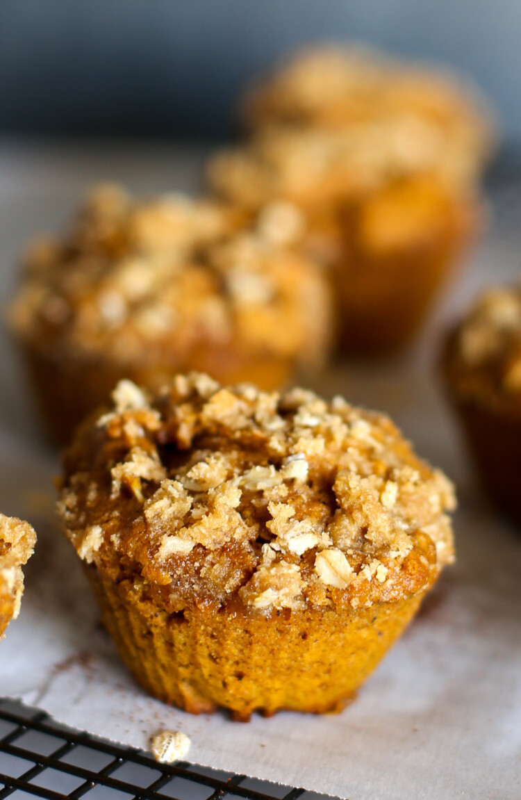 Pumpkin spice muffin with crumble topping on parchment paper.