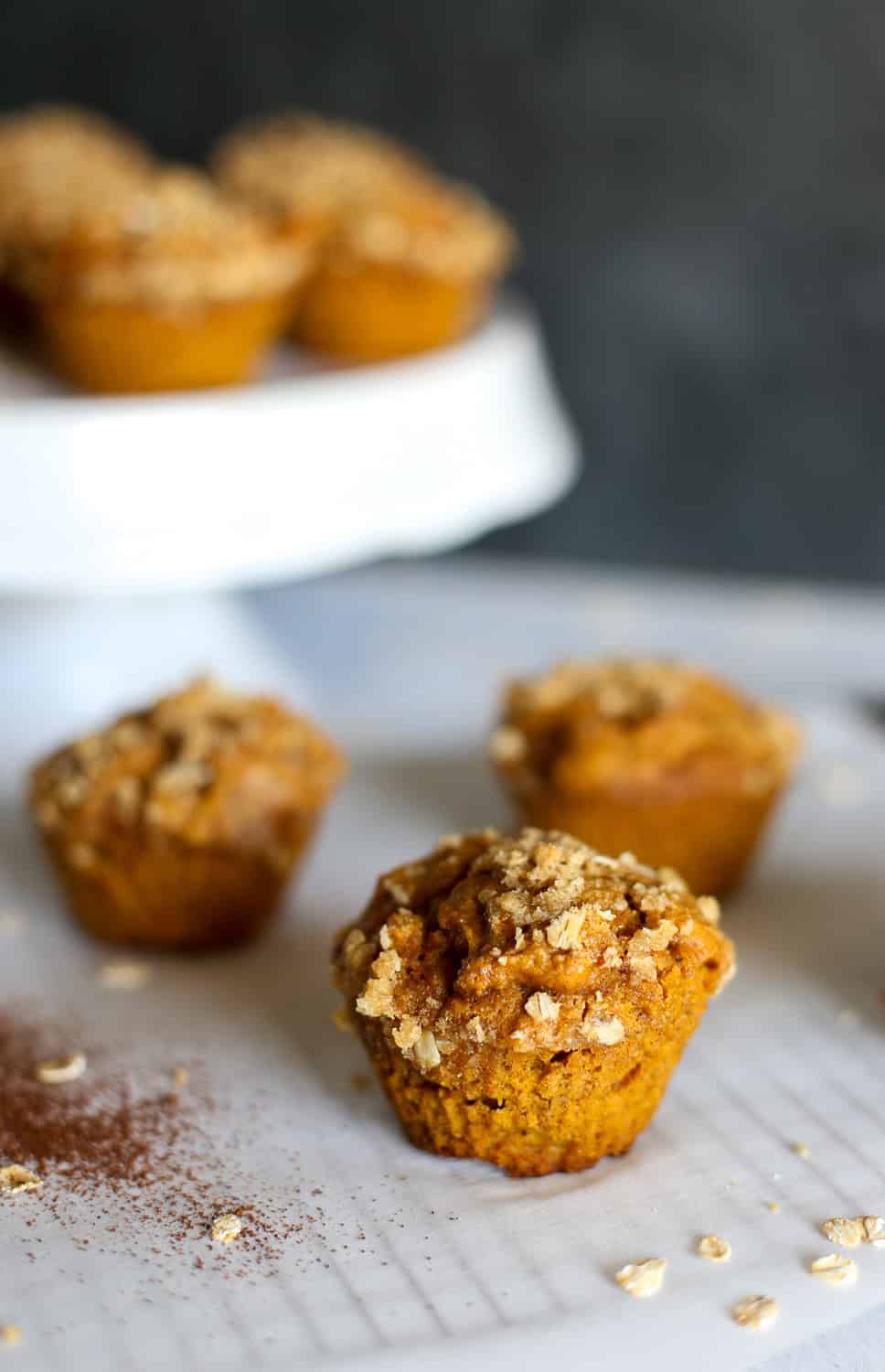 Pumpkin Spice Muffins with a crumble topping sitting on a cooling rack with parchment paper.