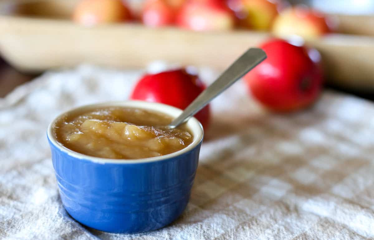 Homemade cinnamon apple sauce in a blue bowl with a spoon.