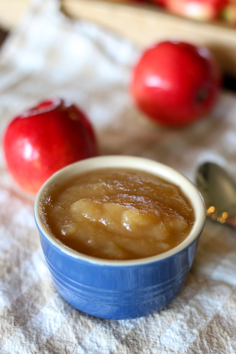 Crockpot cinnamon apple sauce in a small bowl with apples next to it.