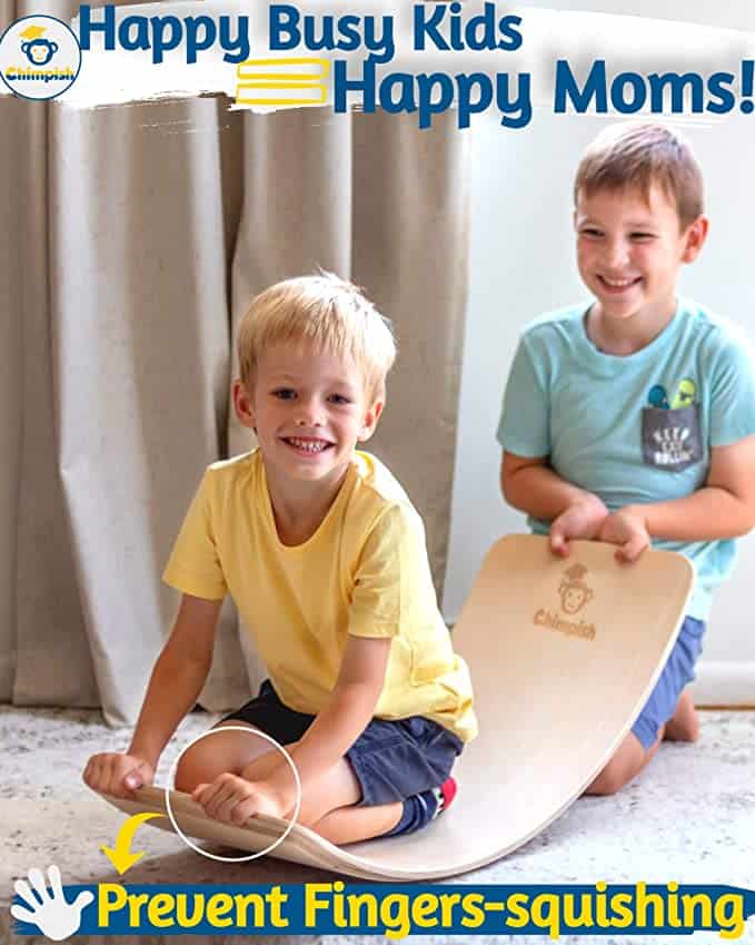 Two kids sitting on a Wooden Wobble Board which is an arched piece of wood that can be used in a variety of ways.